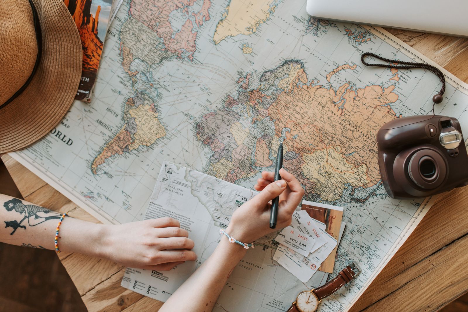 Hands planning on a world map with a notebook and a camera