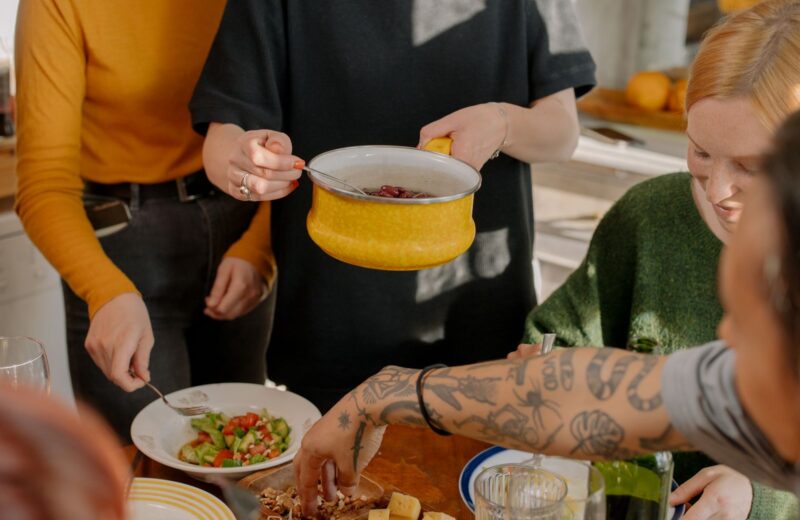 Friends sharing a vegetable dish at a kitchen table