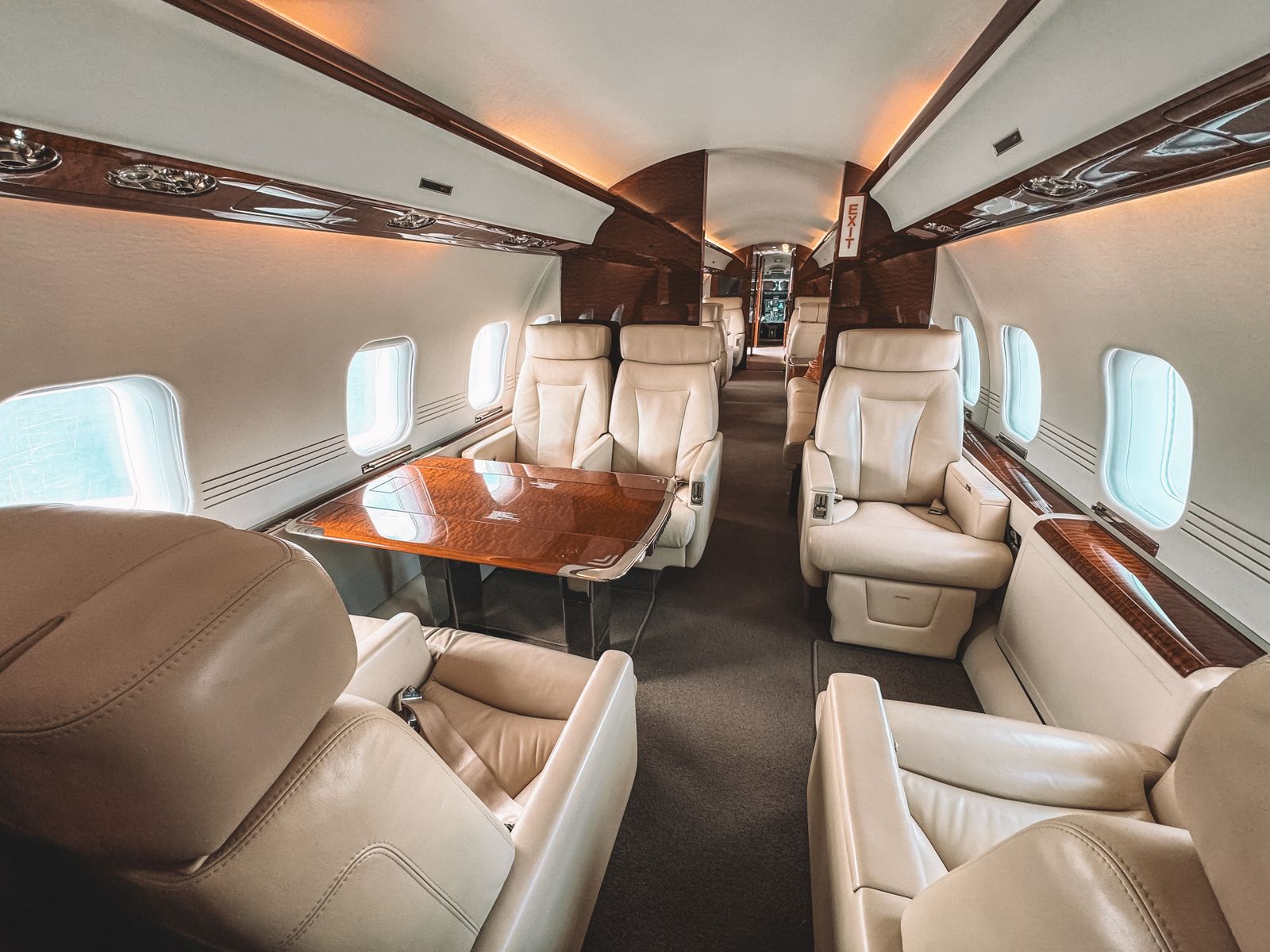 Cabin of a business jet with cream leather seats around a polished table