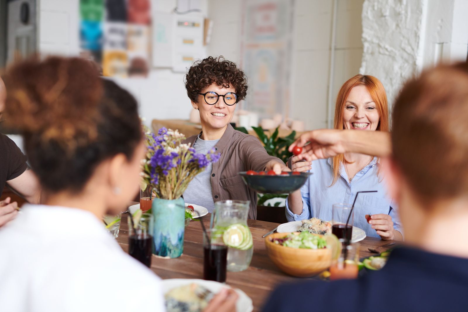 Friends sharing dishes around a table at lunch, passing plates across