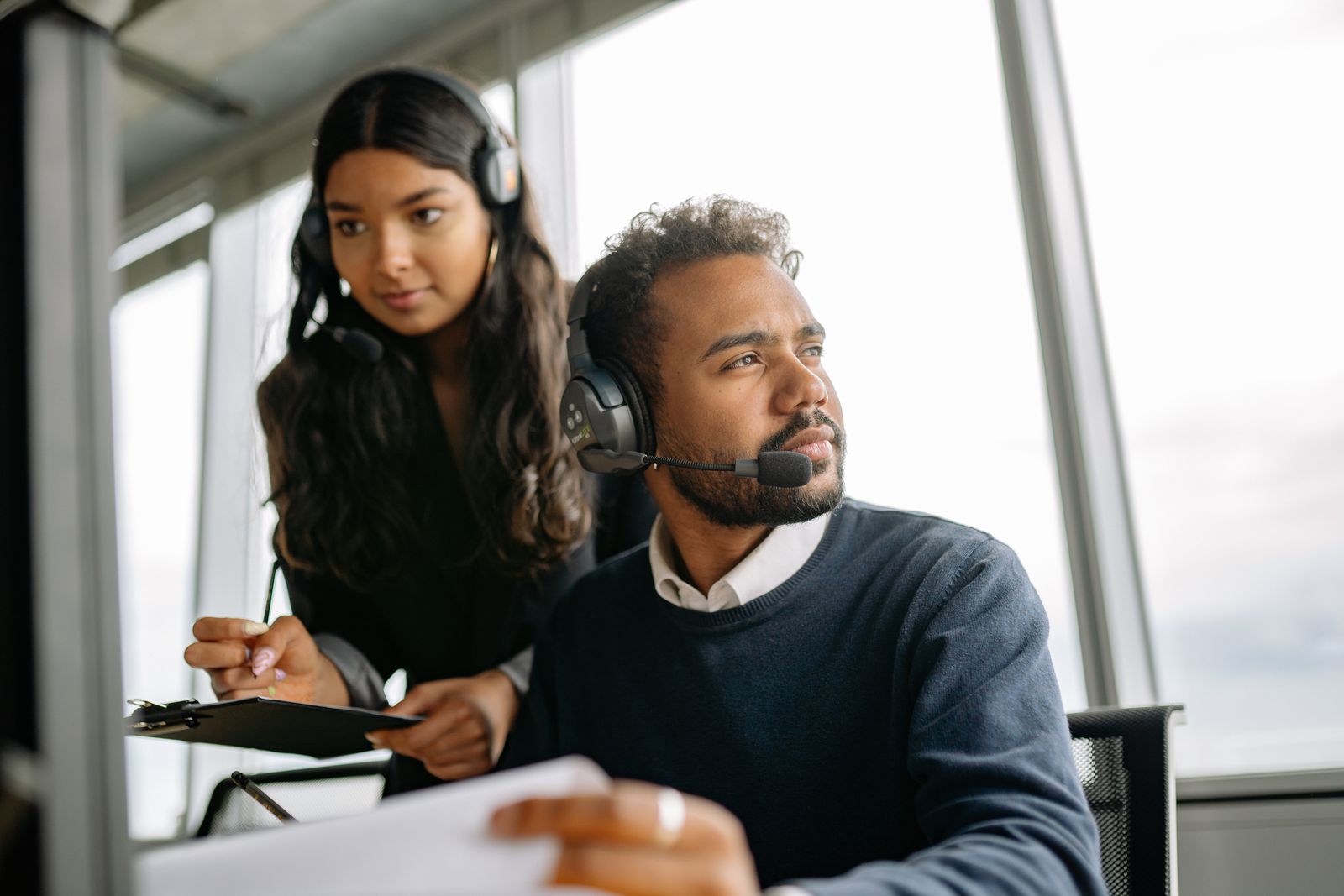 Two support team members with headsets working together at a desk