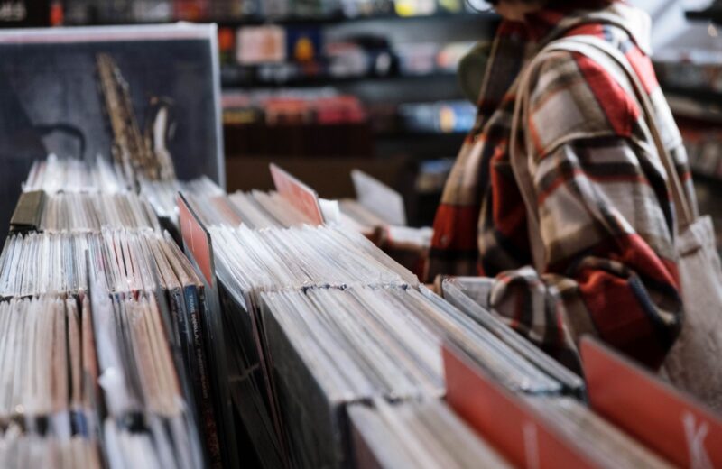A hand flicking through second-hand records in a shop