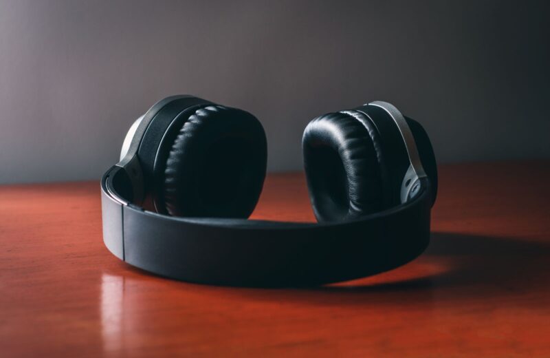 A pair of closed-back headphones lying on a wooden table