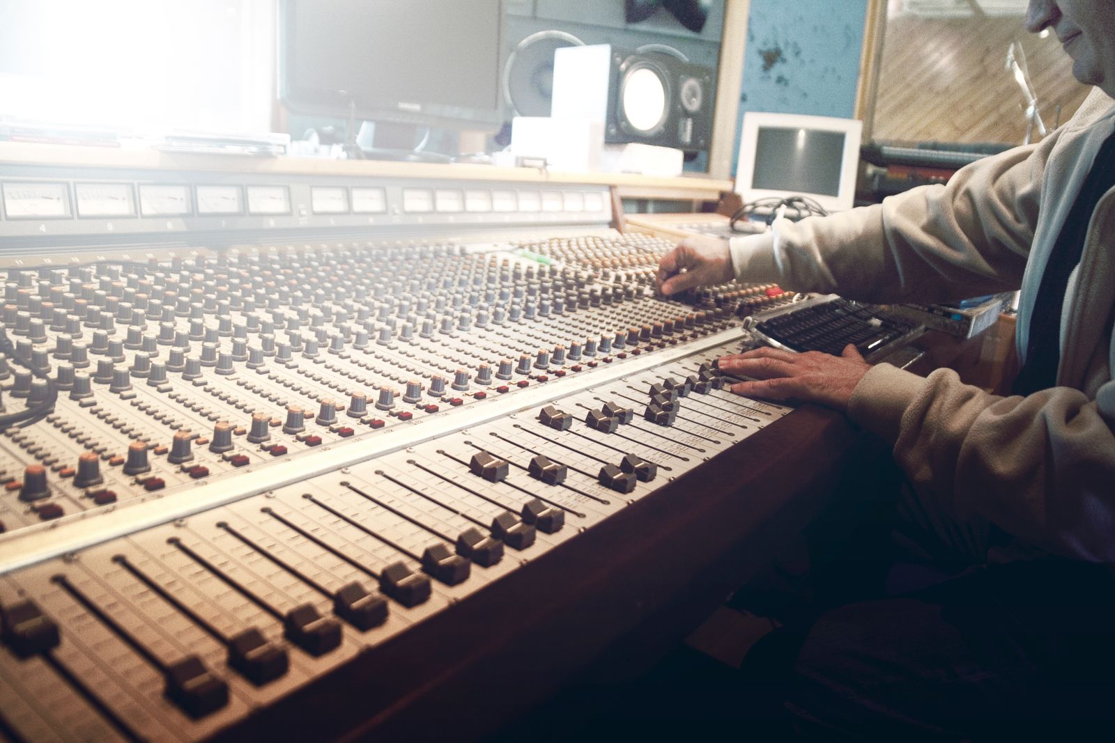 A sound engineer's hands on the faders of a large mixing console