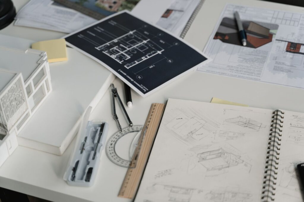 Desk with sketchbooks, a printed plan, protractor and card models