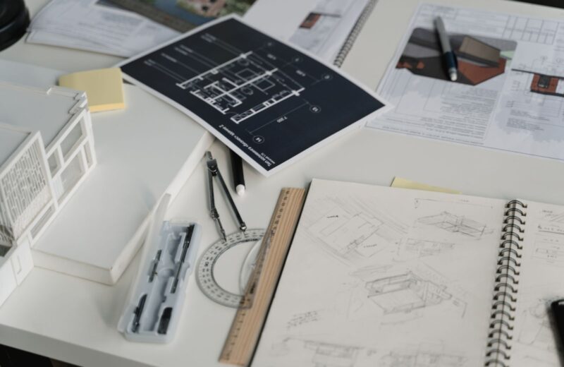 Desk with sketchbooks, a printed plan, protractor and card models