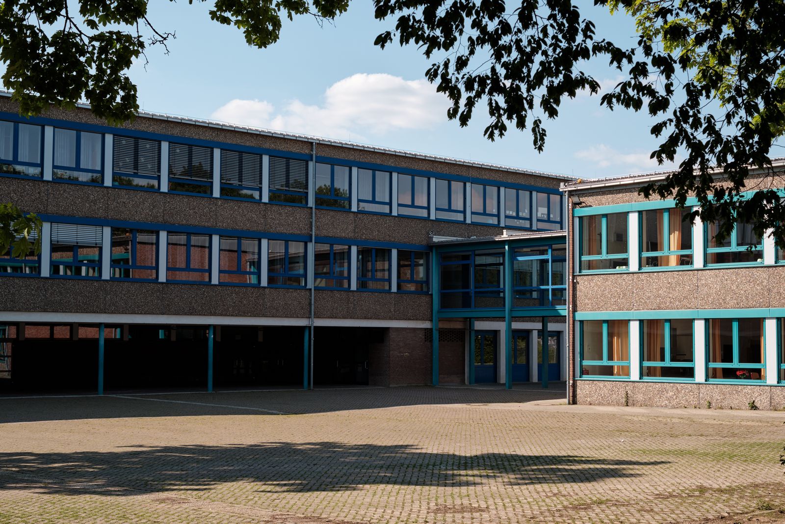 Modern school building with large windows and a paved courtyard