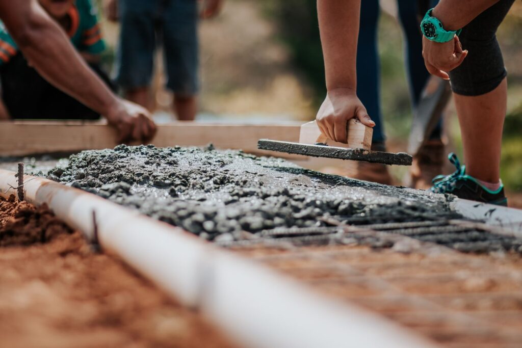 Builders levelling fresh concrete along the edge of a slab