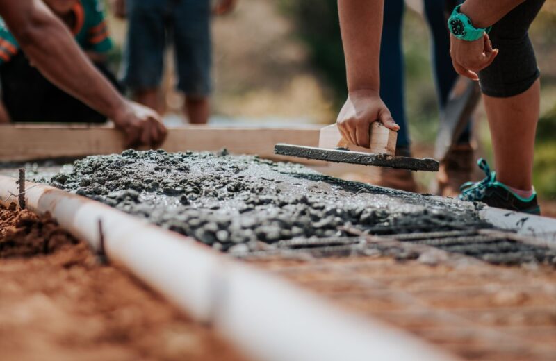 Builders levelling fresh concrete along the edge of a slab