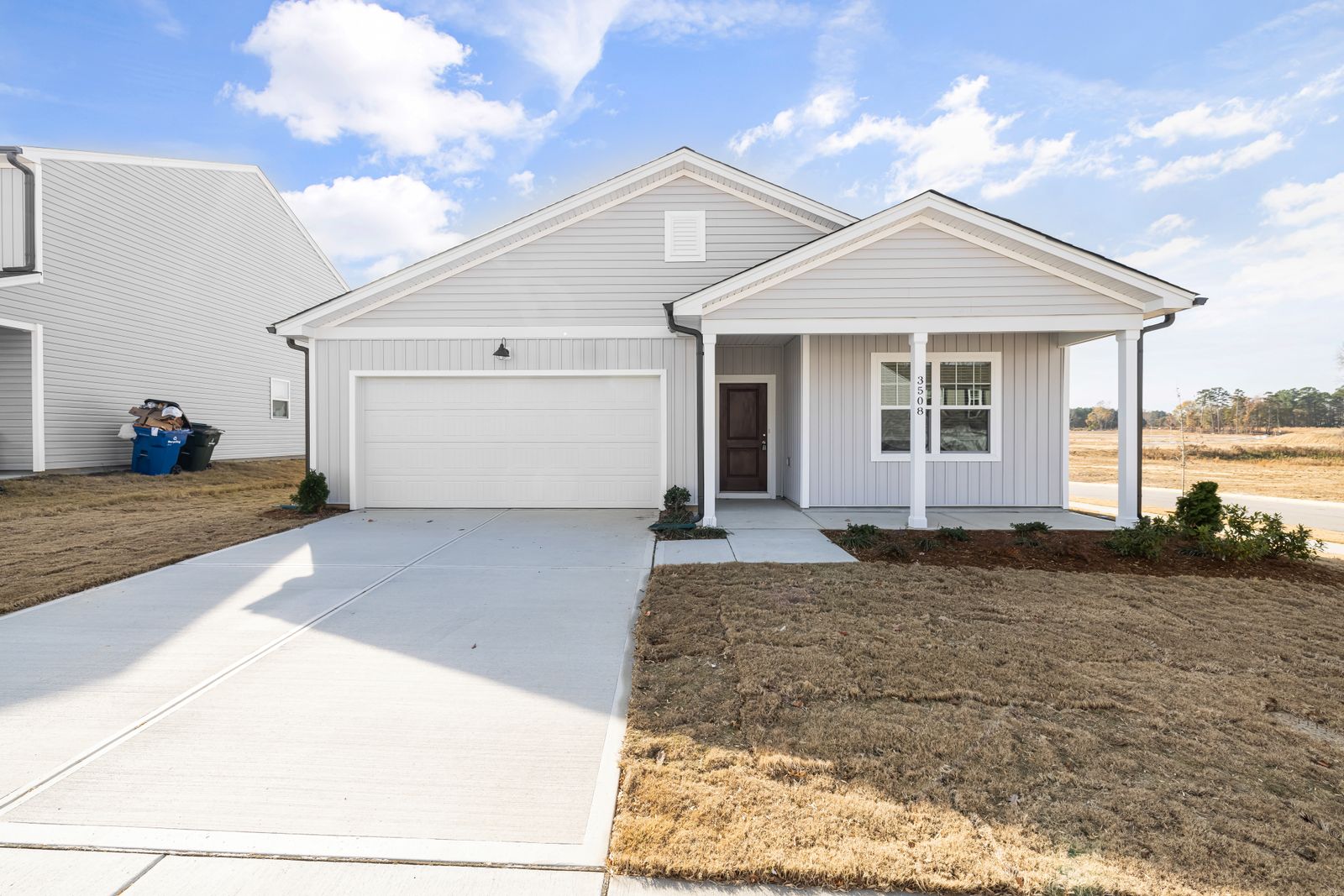 Single-storey family home with a white garage door, a front porch and a new driveway