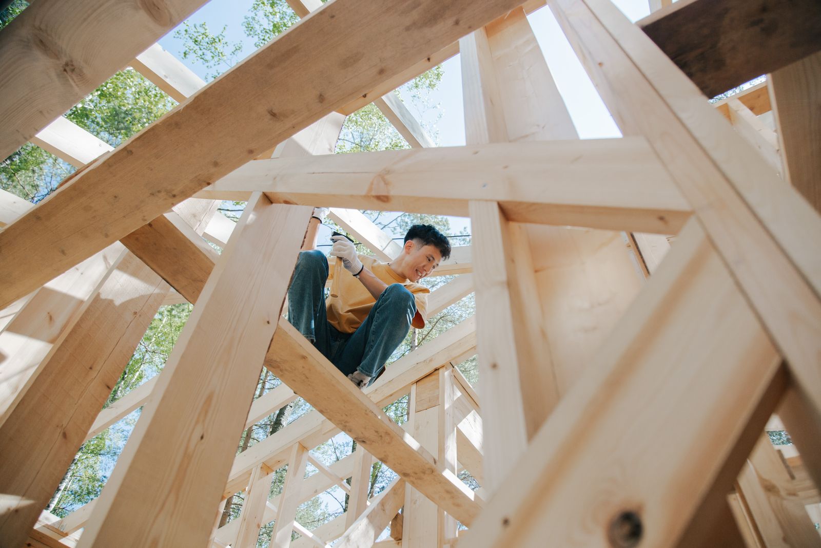 A carpenter working on the timber frame of a house in the sun