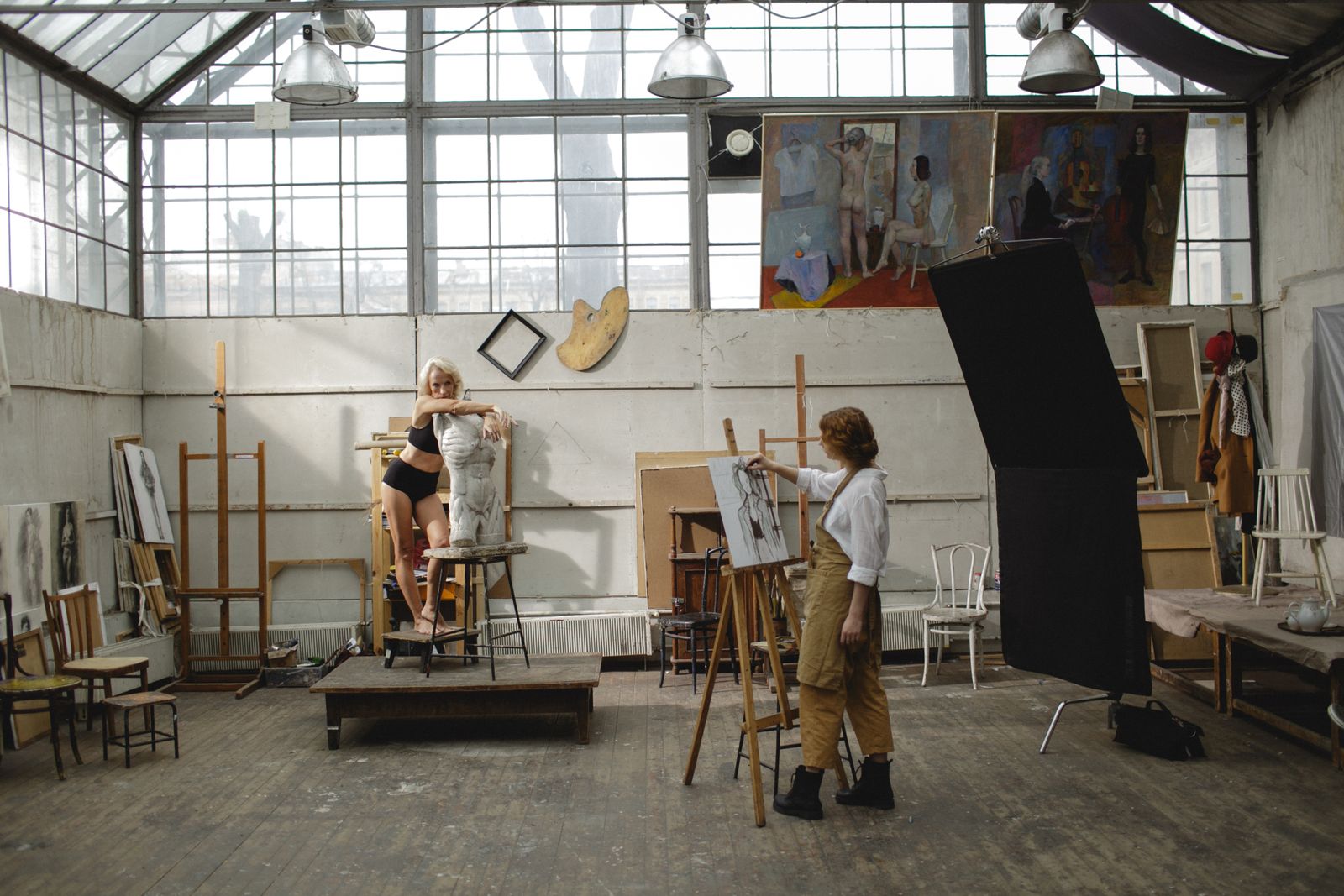 Artists drawing at easels in a large studio with a glass roof