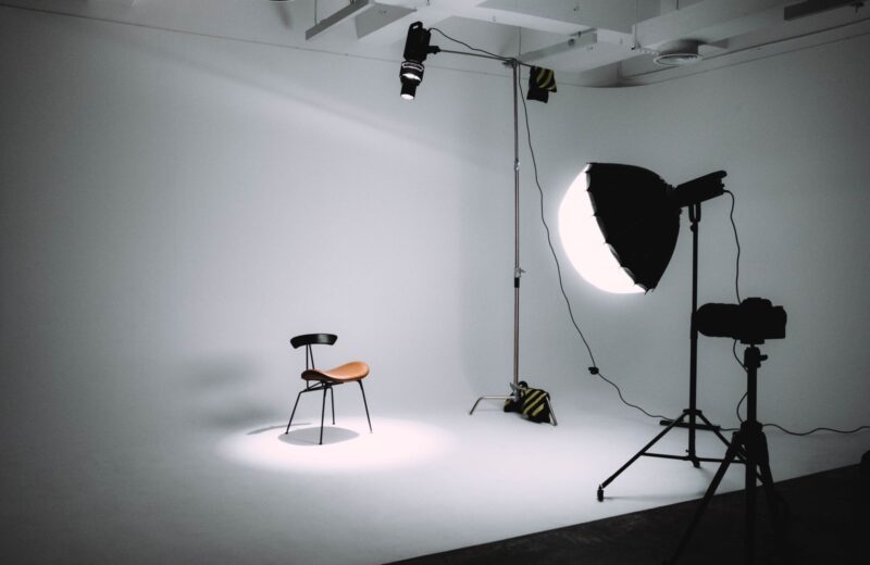 Empty studio with a chair on a white backdrop and lights around it