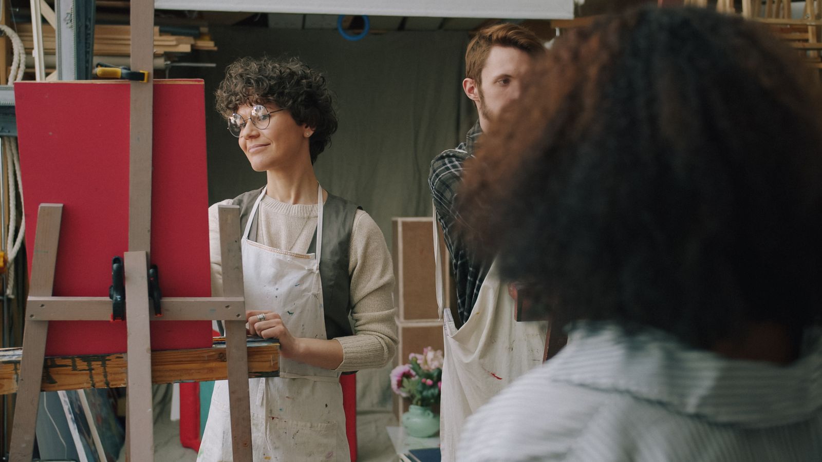 A tutor talking to a small adult class working at easels in a bright studio