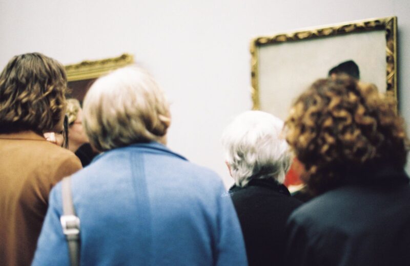 Visitors seen from behind looking at a framed painting
