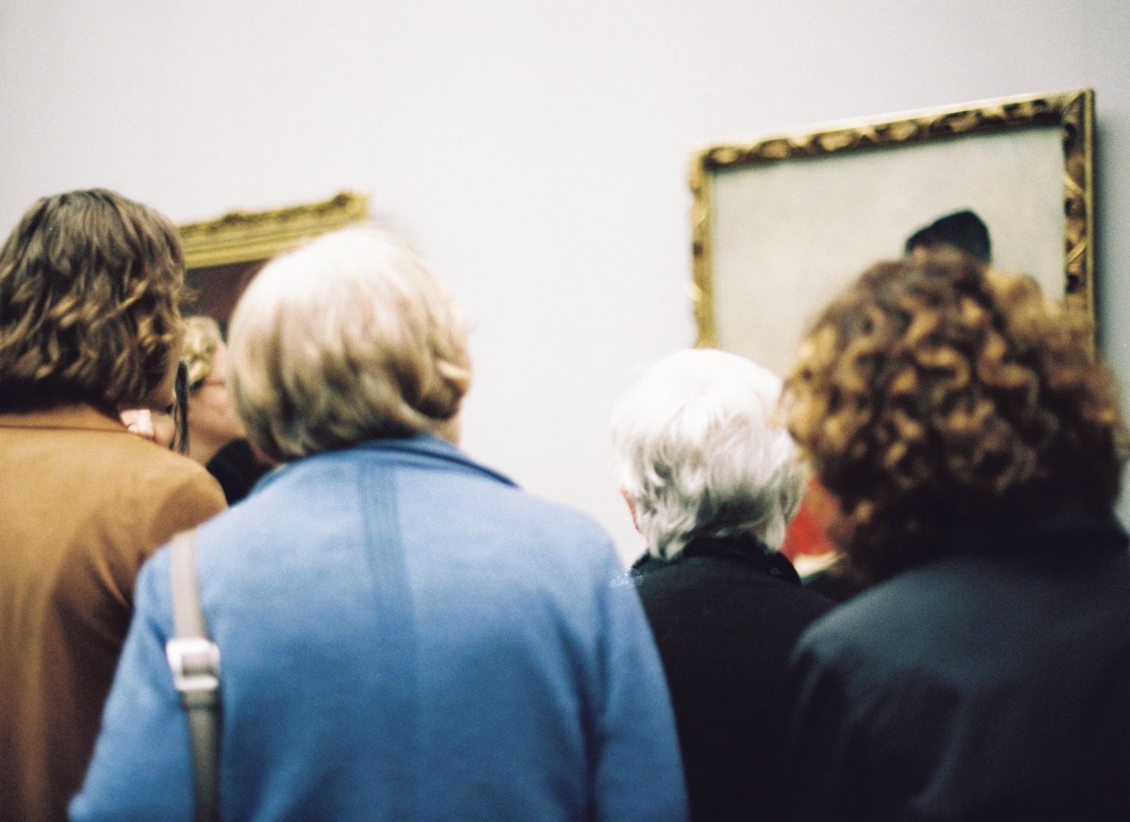 Visitors seen from behind looking at a framed painting