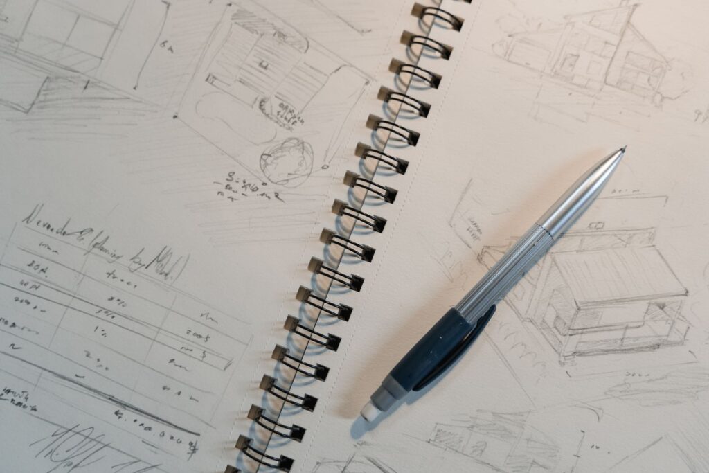 A spiral notepad of pencil sketches with a mechanical pencil on top