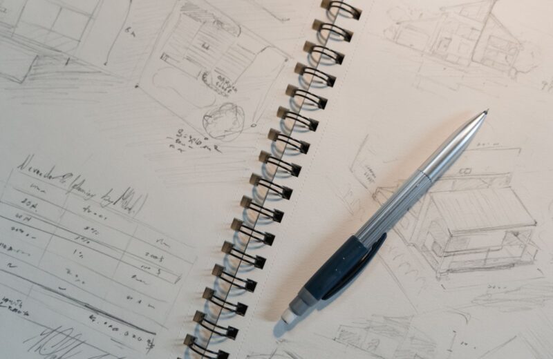 A spiral notepad of pencil sketches with a mechanical pencil on top