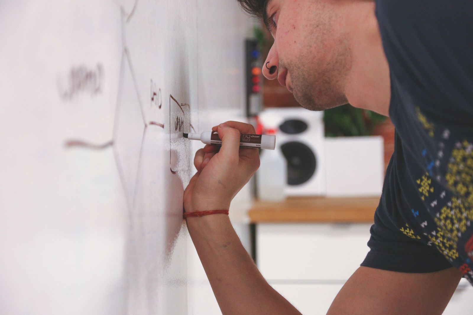 Close-up of a man writing notes on a whiteboard with a marker