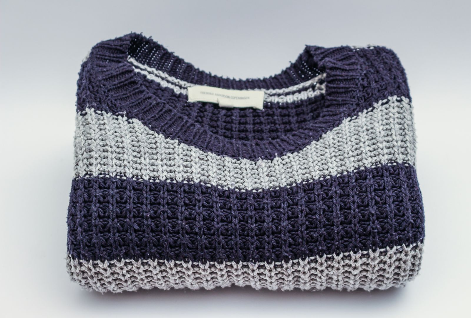 A folded jumper knitted in navy and grey stripes