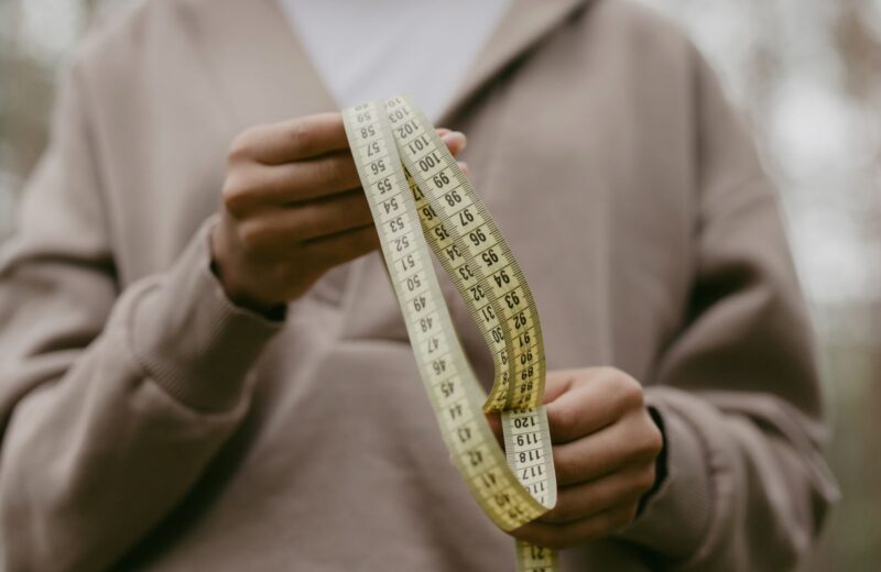 Hands holding a yellow tailor's measuring tape