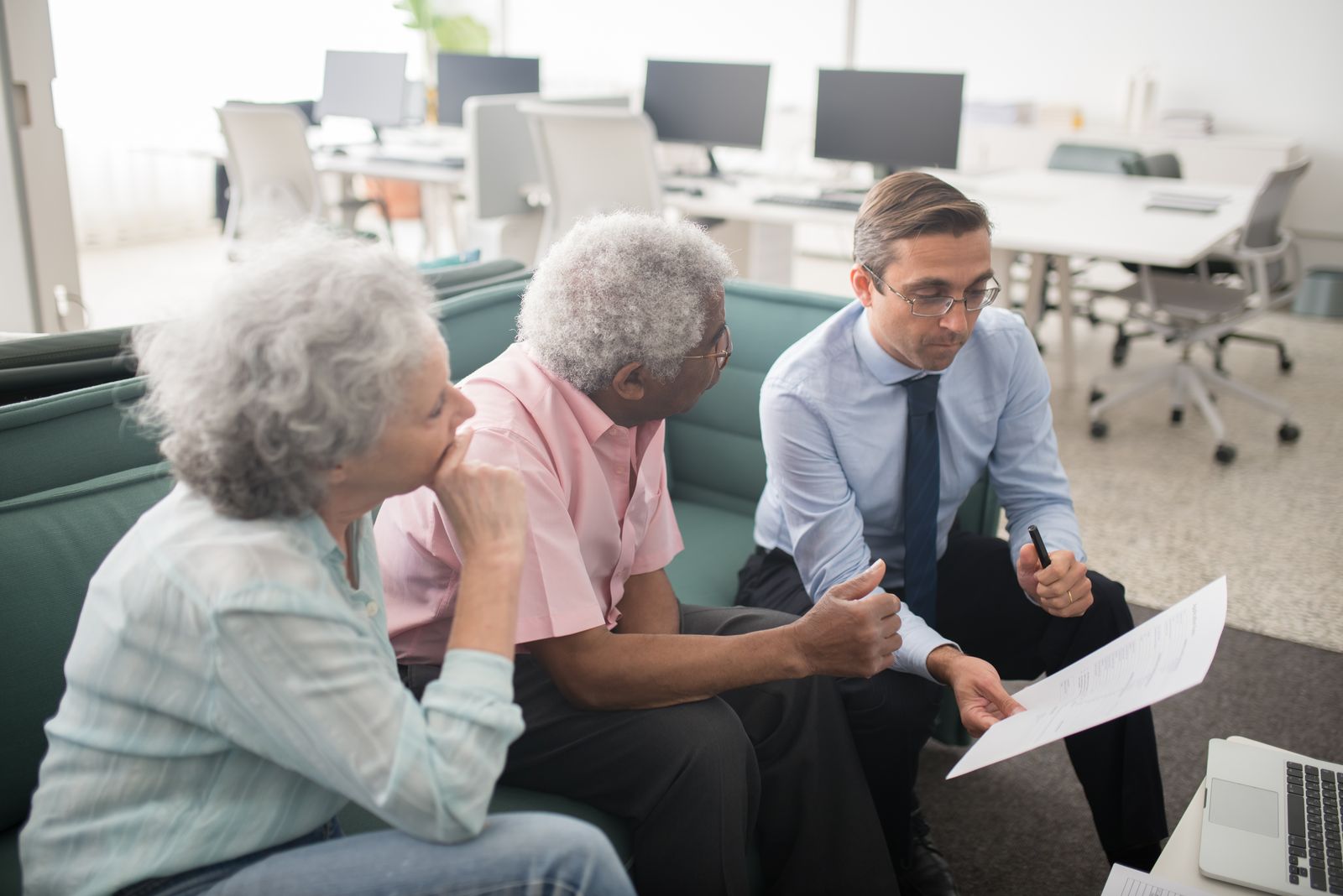 An adviser going through papers with an older couple on a sofa in an office