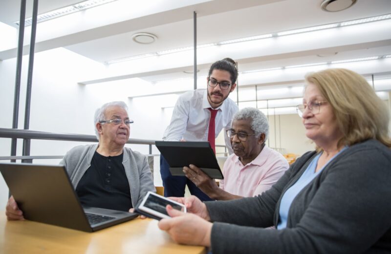 Older adults learning to use tablets and laptops at a library workshop