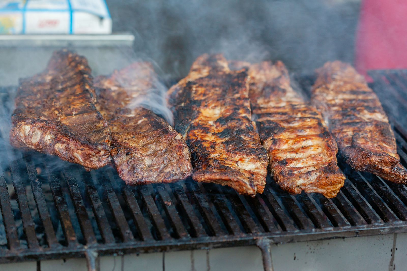 Racks of pork ribs with a dark glaze on a smoker grate