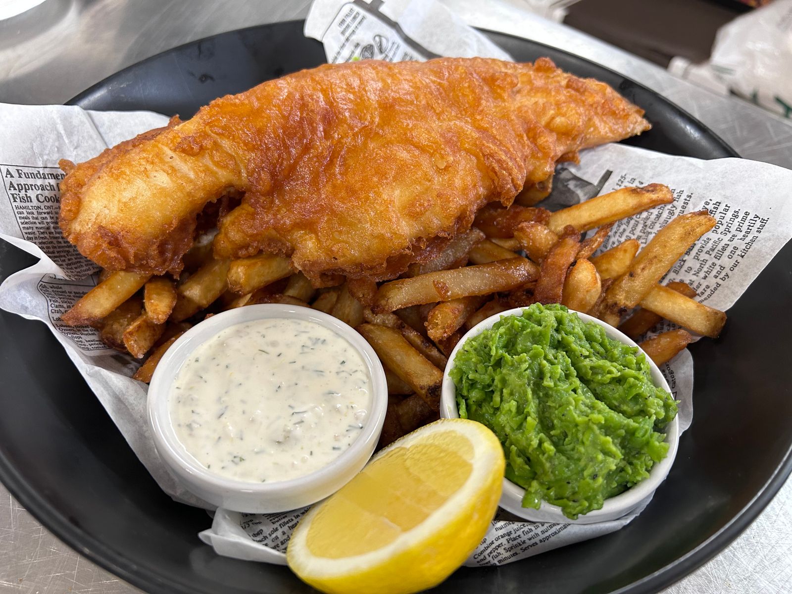 Battered fish and chips with mushy peas, tartare sauce and lemon