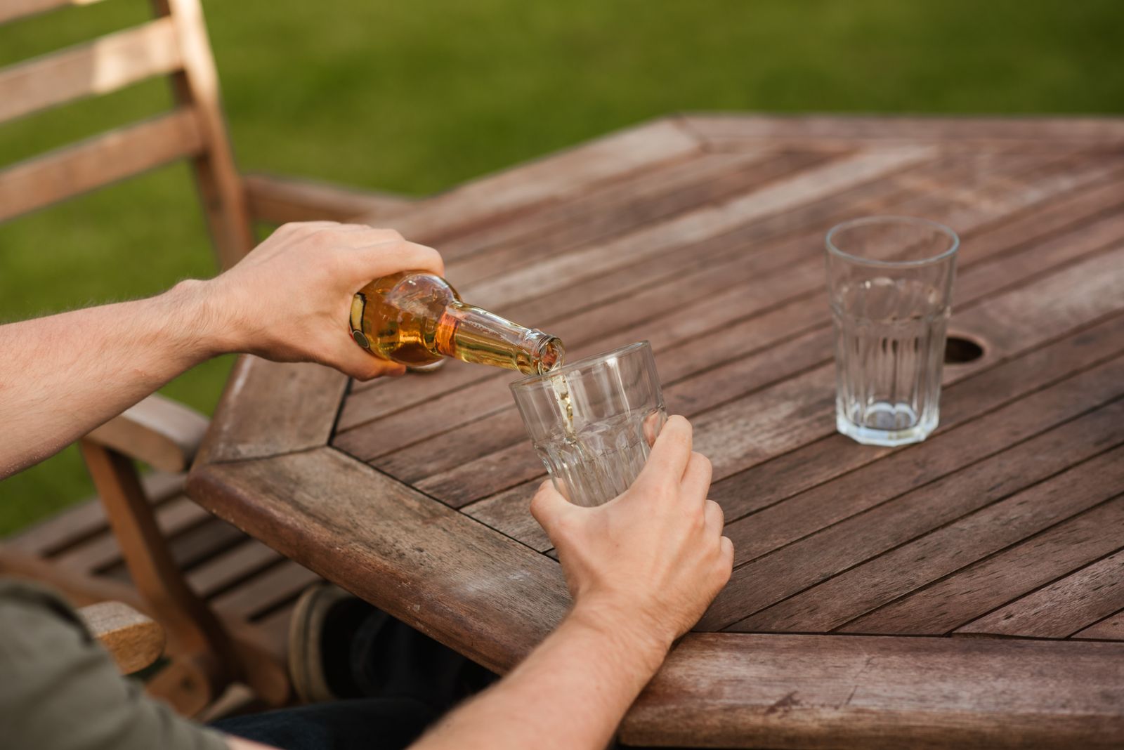 Pouring a beer into a glass at a wooden table in a pub garden