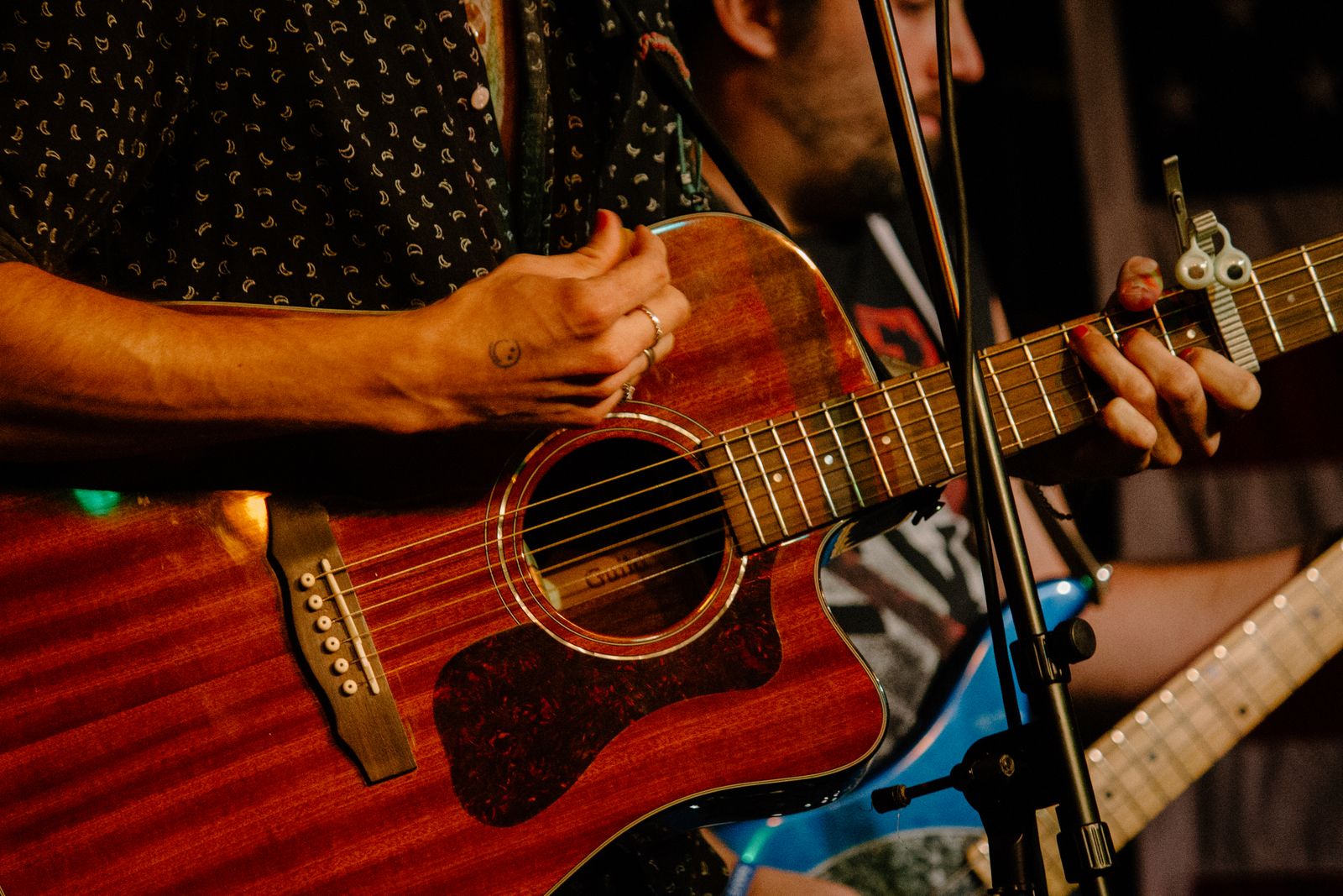 Hands playing an acoustic guitar at a live music night