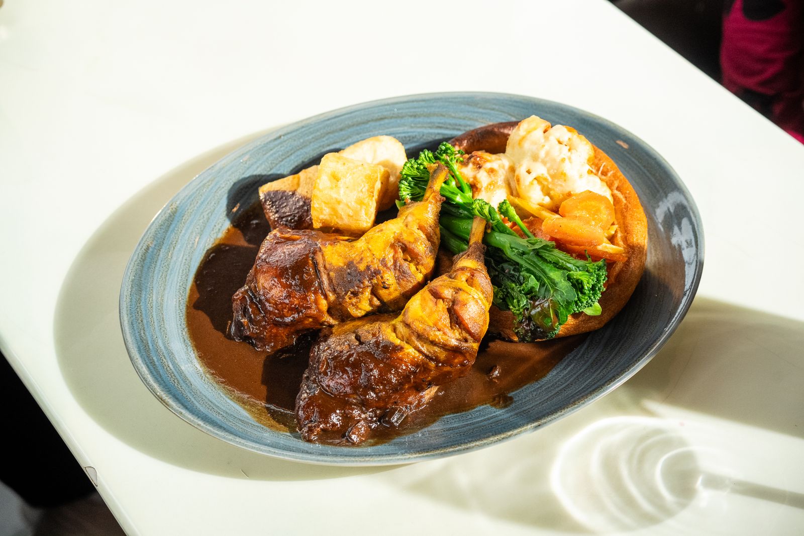 Roast beef with roast potatoes, vegetables and gravy on a white plate