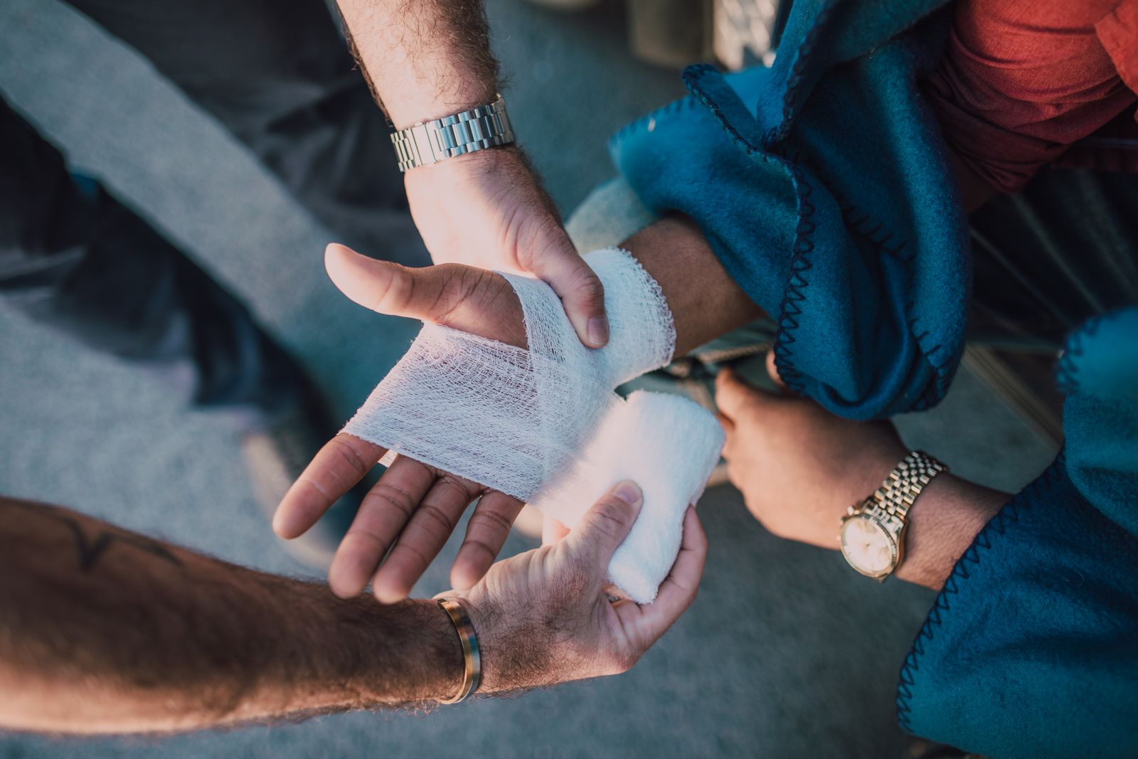 Close-up of hands wrapping a gauze bandage around another person's hand