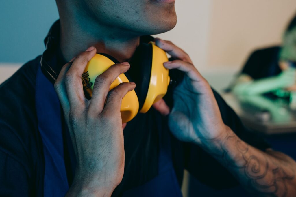 A worker in a navy shirt putting on yellow ear defenders