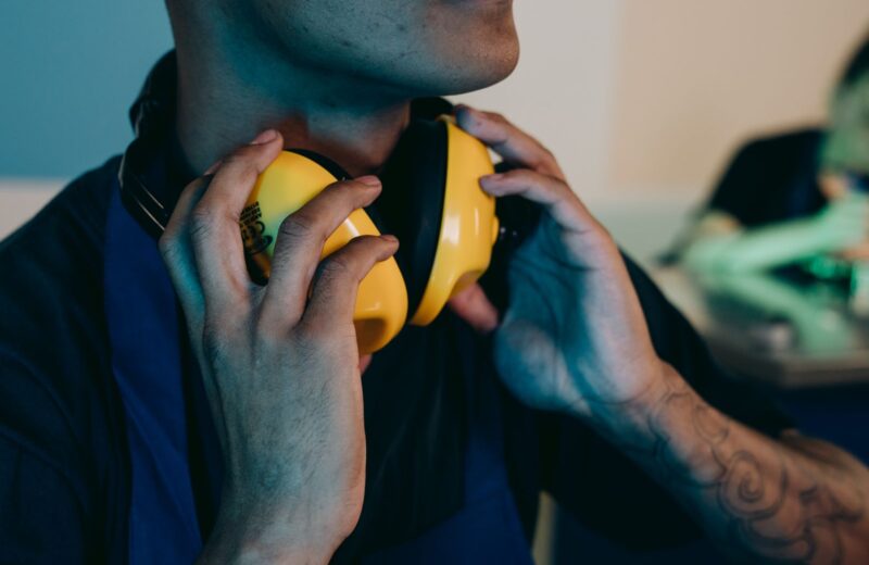 A worker in a navy shirt putting on yellow ear defenders