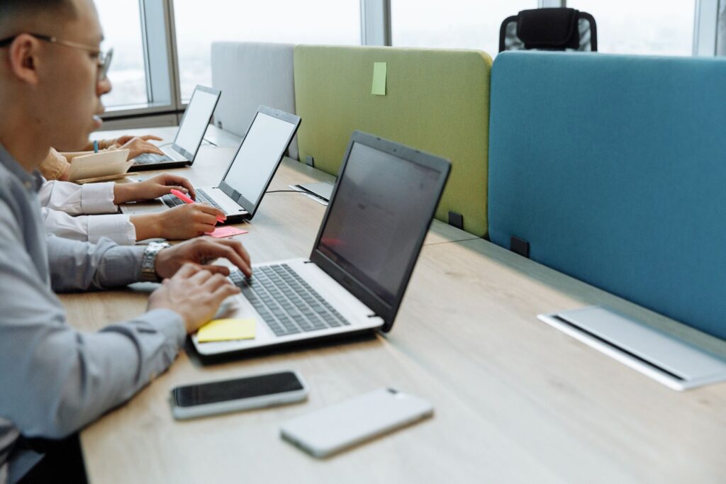 Hands typing on laptops at a shared desk
