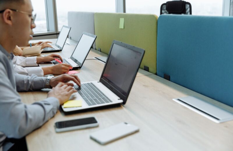Hands typing on laptops at a shared desk