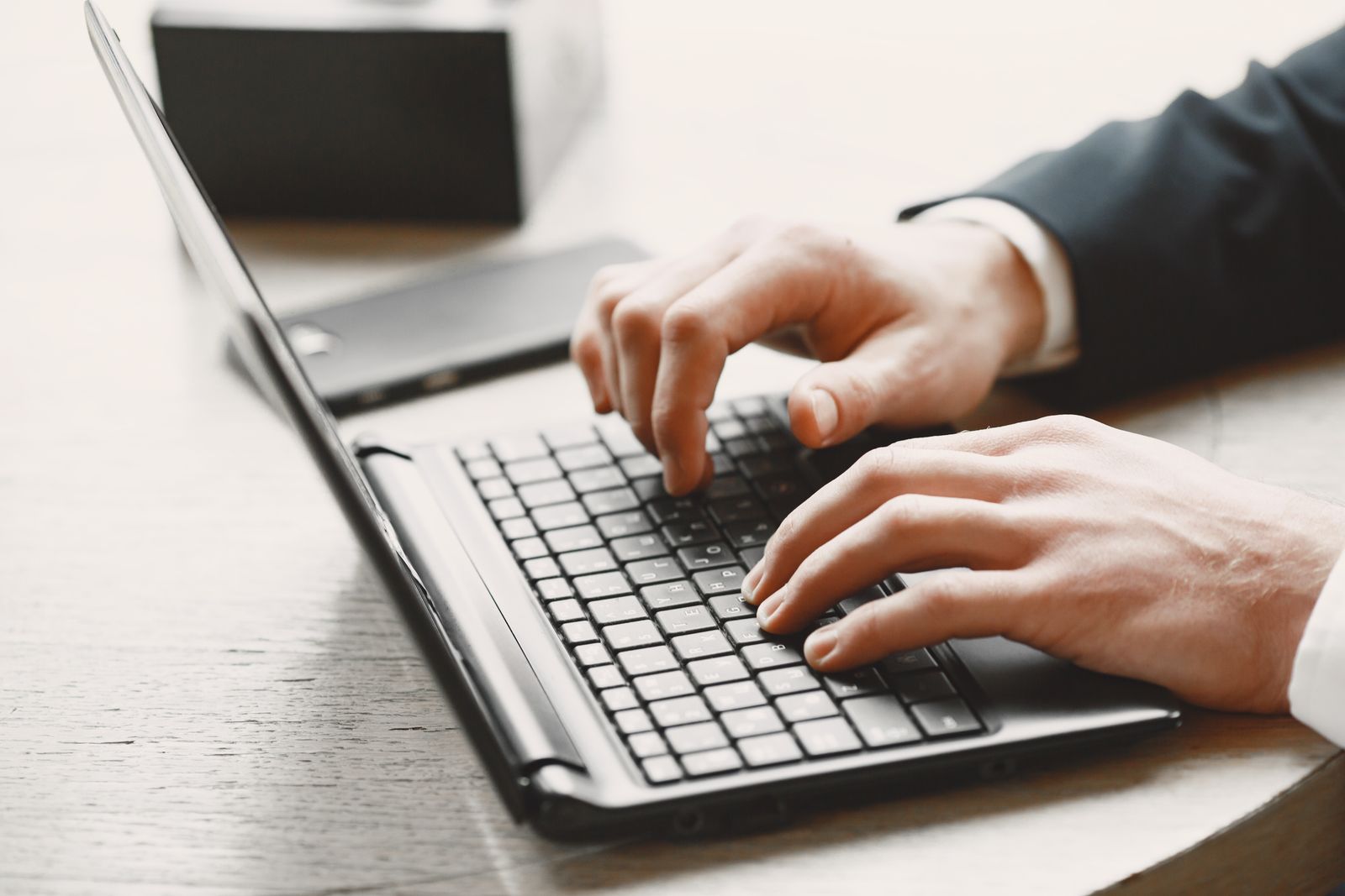 Hands typing on a laptop keyboard at a desk