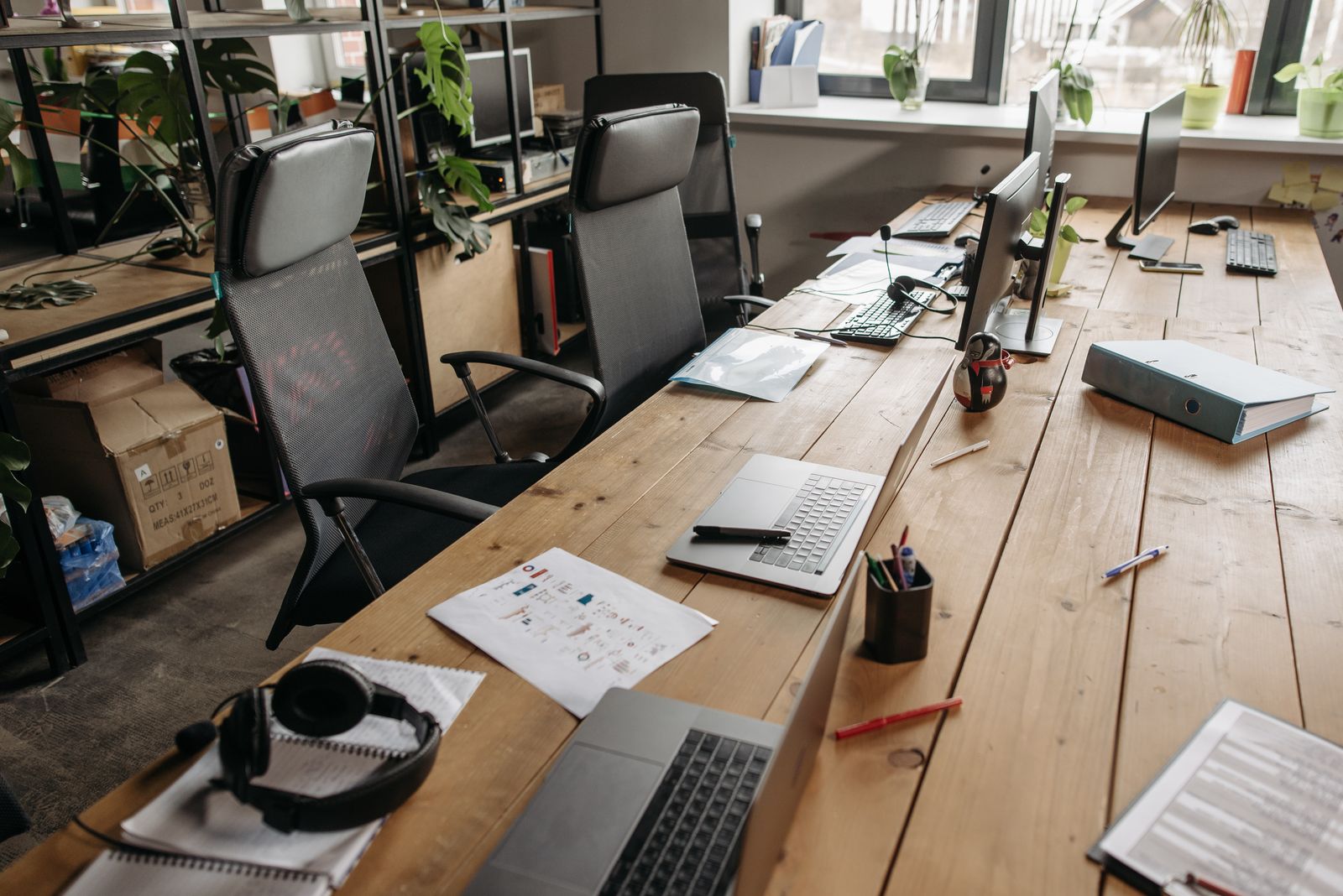 Shared office desks with laptops, monitors and a headset after work