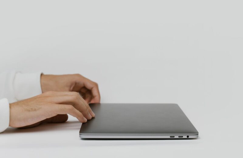 Hands about to open a closed laptop on a bare desk