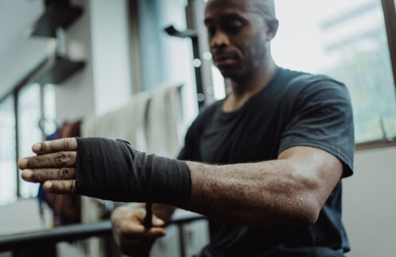 A man wraps his hand in black hand wraps before training