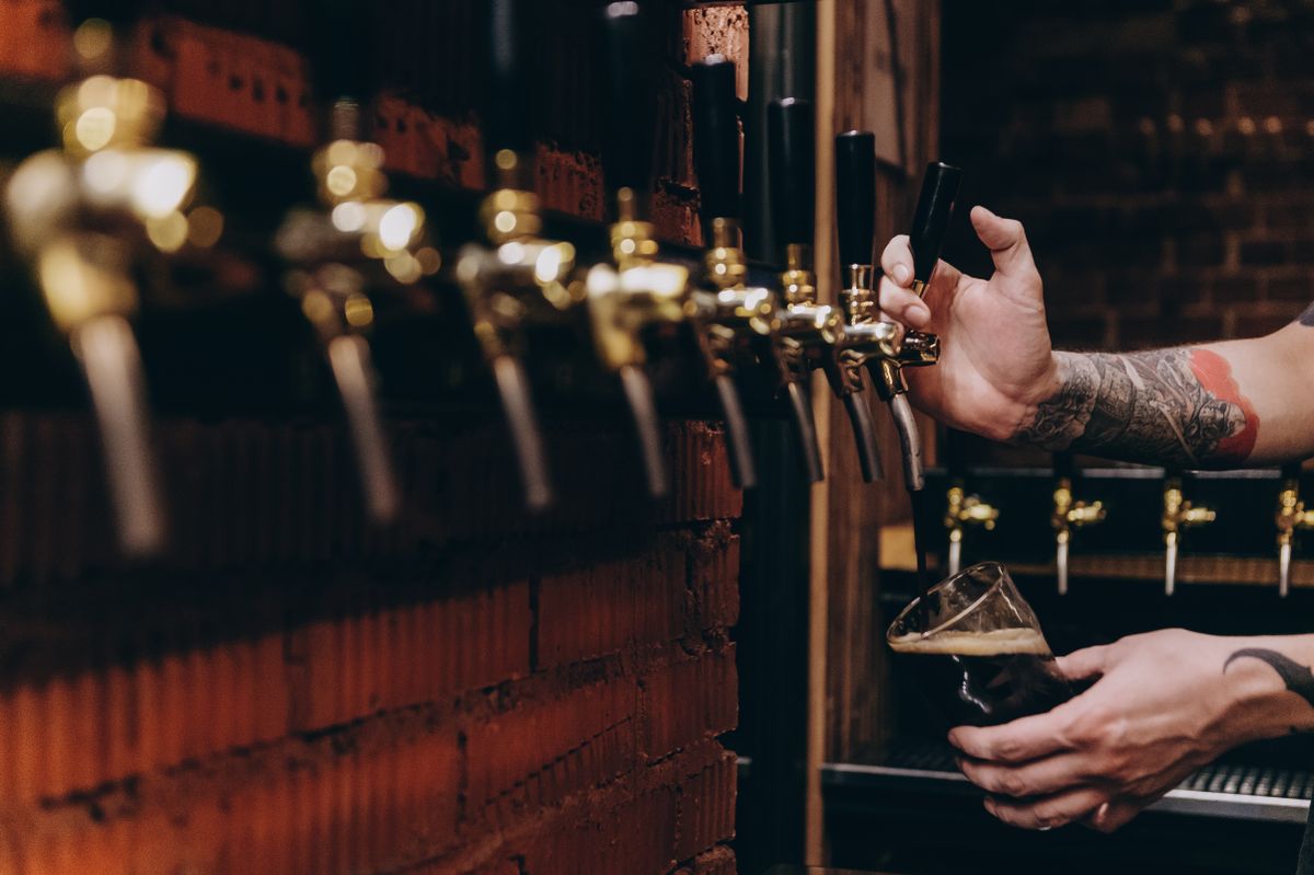 Beer being poured from a tap into a glass at a rustic bar
