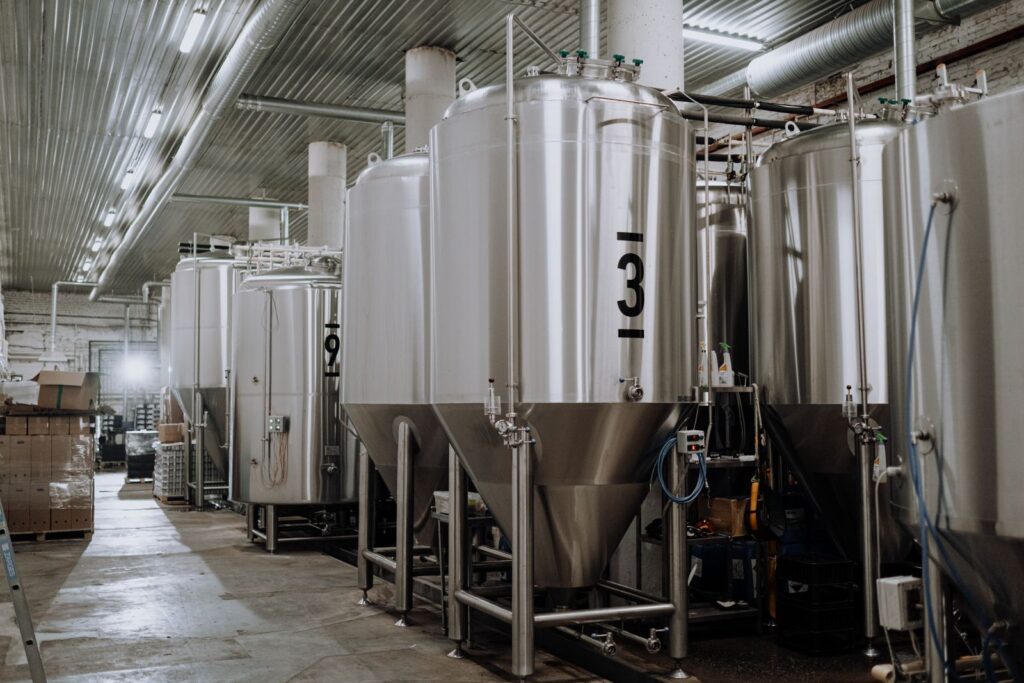 Rows of tall steel fermentation tanks on the brewery floor
