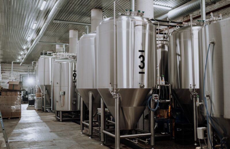 Rows of tall steel fermentation tanks on the brewery floor