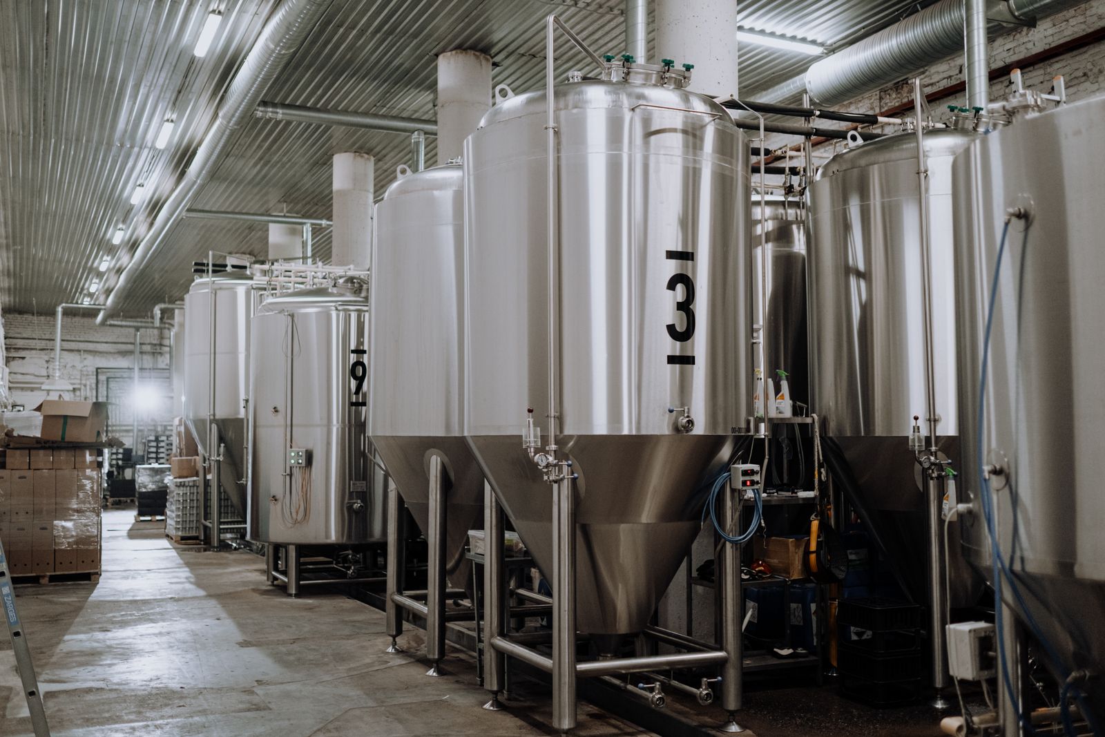 Rows of tall steel fermentation tanks on the brewery floor