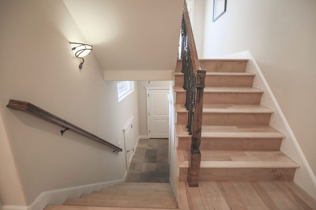 A wooden staircase with a sturdy handrail in a light hallway