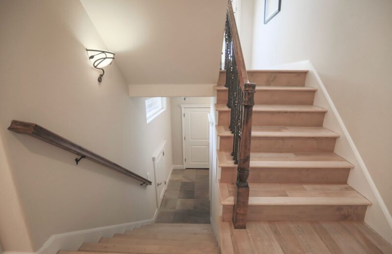 A wooden staircase with a sturdy handrail in a light hallway