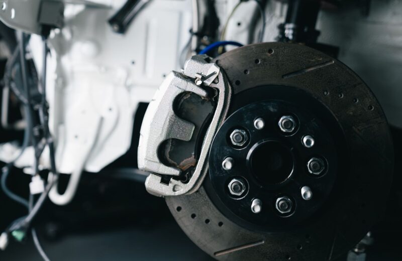 A drilled brake disc and caliper on a car in the workshop