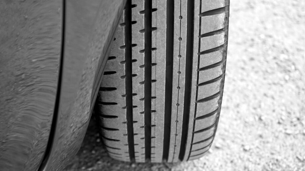 A car tire standing on gravel, its tread pattern in sharp focus