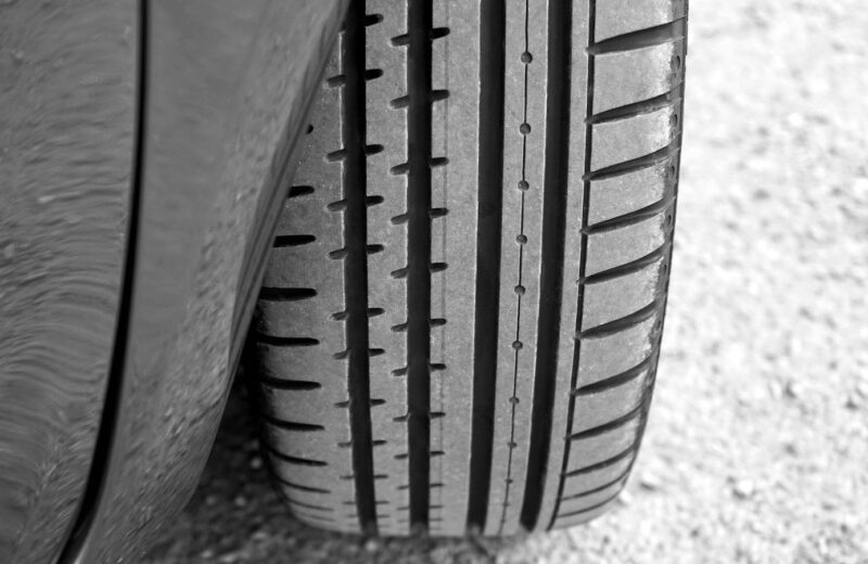 A car tire standing on gravel, its tread pattern in sharp focus